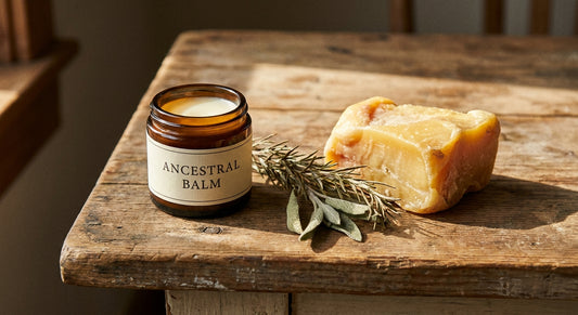 A rustic close-up of a glass jar filled with creamy tallow balm beside raw tallow fat and dried herbs on a warm wooden surface.